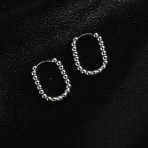 Detailed view of silver beaded hoop earrings on black silk texture background