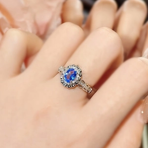 3 carat oval blue sapphire ring with halo diamonds on silver band worn by model