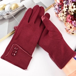 Detail view of burgundy thermal gloves with decorative buttons and touchscreen fingertips
