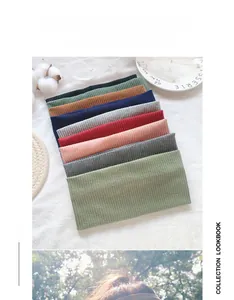 Close-up of ribbed knit headbands in various colors on a textured white fabric background
