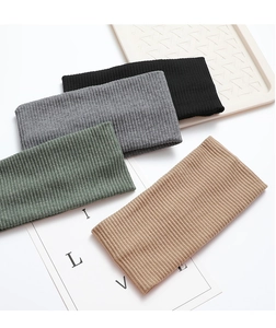 Close-up of four ribbed knit headbands in black, grey, green and khaki on a white tray