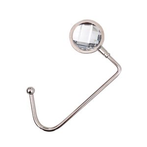 Macro detail of silver metal table hook featuring a clear faceted crystal decorative top