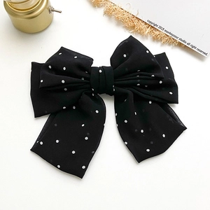 Detailed view of a multi-layered black polka dot bow hair clip on a clean background