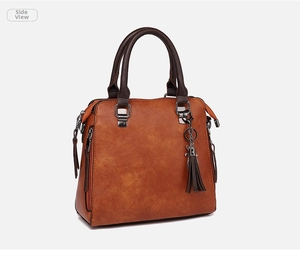 Détail du sac cabas en cuir vintage avec texture grainée et breloque en métal chiot