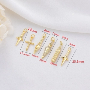 Detailed size view of gold-plated dagger and cross charms on white fabric background
