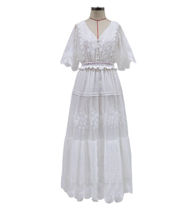 Detail of white lace dress featuring V-neckline, intricate embroidery and tiered skirt