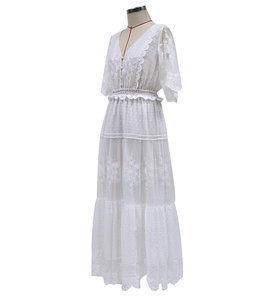 Detailed view of white floral lace embroidery and delicate polka dot texture on V-neck dress
