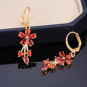 Detailed close-up of flower earrings with gold base and ruby-red zircon gemstones