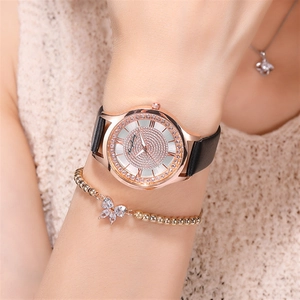 Detail of rose gold quartz watch with diamond dial and black leather strap on wrist
