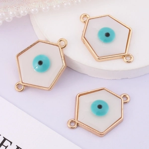Detailed macro view of three white hexagonal evil eye charms with gold enamel finish
