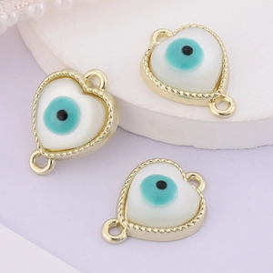 Close-up of three heart-shaped evil eye charms with gold frames and white shell inlays