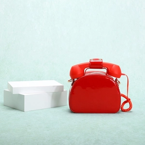 Close-up of a creative red telephone-shaped handbag with glossy finish and retro handset handle