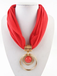 Dettaglio della sciarpa collana in tessuto rosso con ciondolo a doppio anello d'oro