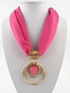 Dettaglio della collana foulard rosa con tripli anelli dorati e perlina di gemma centrale