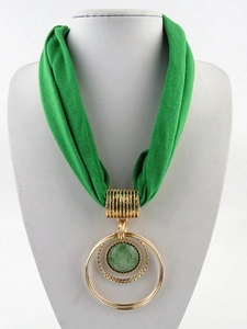 Dettaglio della collana a sciarpa verde con anelli dorati e pietra verde centrale