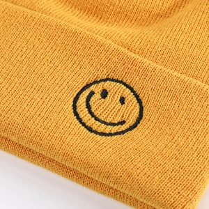Winter mustard yellow knitted beanie with a black smiley face embroidery and ribbed texture