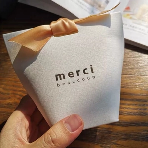 Elegant white textured gift box with orange ribbon and merci beaucoup gold foil printing