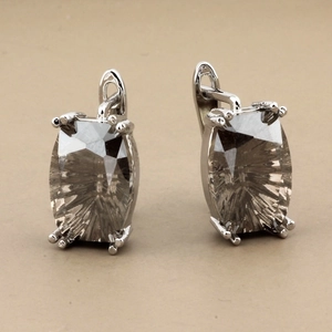 Macro shot of silver earrings featuring radiant-cut dark grey rectangular crystals