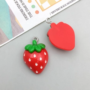 Macro detail of red resin strawberry charms with metal rings for DIY jewelry making