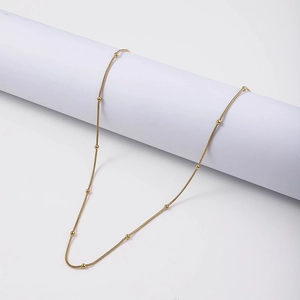 Detail of 18K gold plated stainless steel snake chain with small round beads on white background