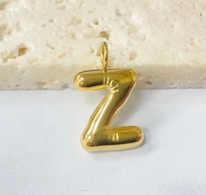 Macro shot of gold chubby bubble letter Z pendant charm with polished finish and bail