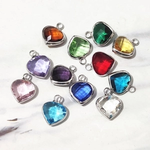 Multicolor heart-shaped birthstone pendants with silver metal frames on marble
