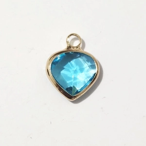 Macro view of blue heart gemstone pendant with gold metal frame for jewelry making