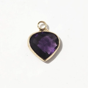 Macro shot of faceted purple heart gemstone pendant with gold frame and metal bail