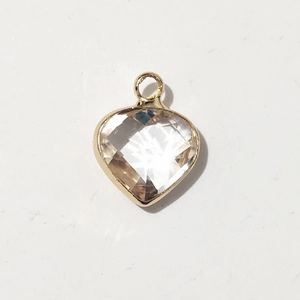 Close-up of a heart-shaped birthstone pendant with golden frame and clear crystal inlay