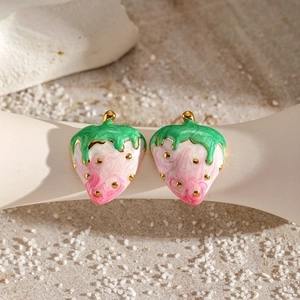 Macro detail of pink strawberry earrings with gold-plated edges and enamel finish