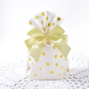 Detail of white OPP gift bag with gold polka dots and a soft yellow ribbon bow