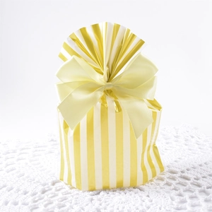 Elegant yellow striped cookie bag with a large satin ribbon bow on a white crochet mat