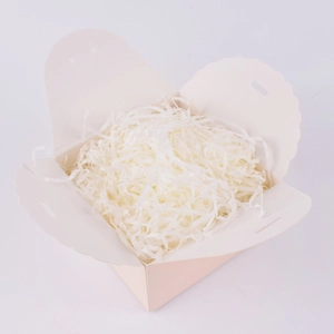 Macro view of white shredded paper filler inside a small cardboard gift box with wavy edges