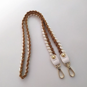 Detail of woven brown and beige shoulder strap with gold metallic thread and leather ends