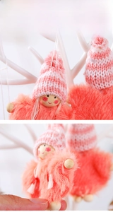 Close-up of a pink plush Christmas doll ornament with knitted hat and wooden face