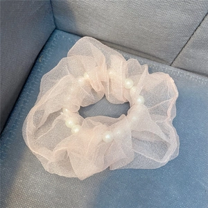 Detailansicht eines rosa Mesh-Haargummis mit weißen Perlen und elastischer Textur