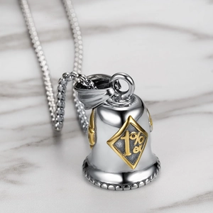 Close-up of vintage 1%er skull motorcycle bell pendant in silver and gold steel