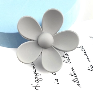 Close-up of a matte grey flower hair claw clip on a stylish decorative background