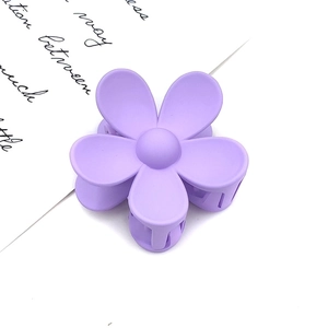 Detail shot of a matte purple flower hair claw clip on a minimalist white background