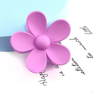 Close-up of a matte pink-purple flower hair claw clip on a stylish decorative background