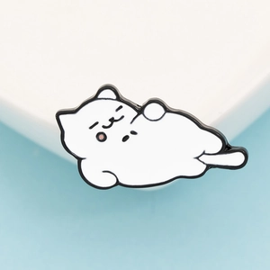 Detail of a cute white sleeping cat enamel pin with black outlines and pink cheeks
