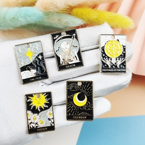 Five-piece tarot enamel charms featuring Sun and Moon designs held in a gloved hand