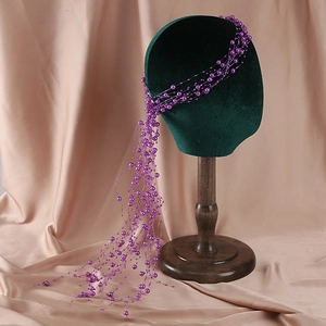 Close-up of handmade purple beaded bridal headpiece with pearls on green velvet mannequin