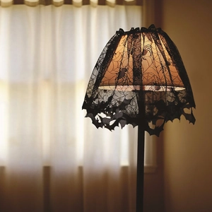 Close-up of black lace lampshade featuring spooky spider web and bat patterns for Halloween