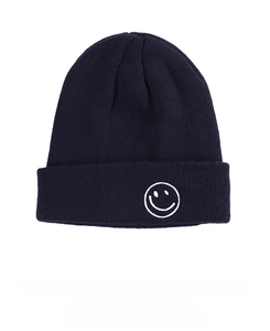 Close-up of navy blue ribbed knit beanie featuring detailed white smiley face embroidery