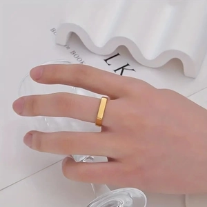 Gold plated stainless steel ring with flat rectangular geometry on a model's hand