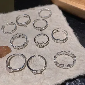 Detailed set of silver S925 rings featuring heart, pearl, and bow designs on textured paper