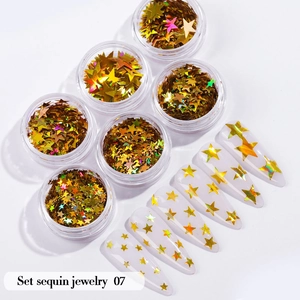Macro detail of six jars of holographic gold star nail sequins and clear application tips