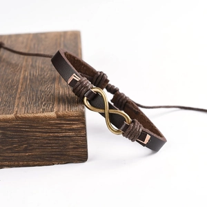 Brown braided leather infinity bracelet with brass hardware displayed on dark wood block