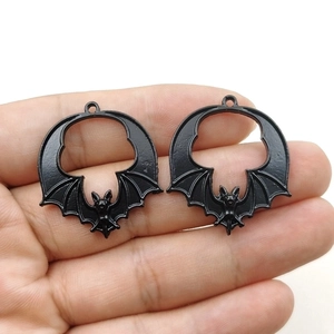 Detail of black metal bat pendant charms with cutout design for DIY jewelry making